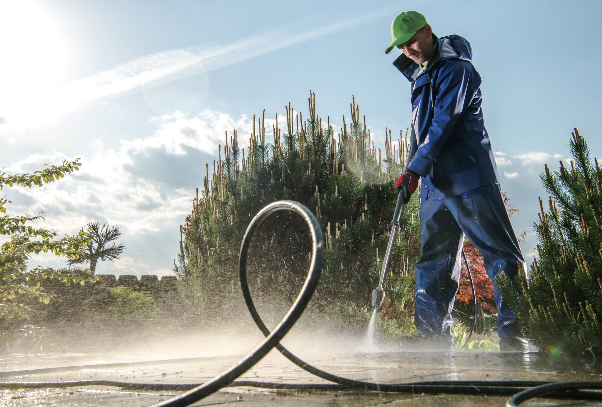 Garden Washing Maintenance. Caucasian Worker in His 30s with Pressure Washer Cleaning Brick Paths.