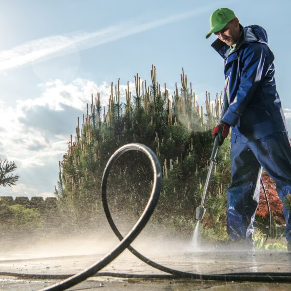 Garden Washing Maintenance. Caucasian Worker in His 30s with Pressure Washer Cleaning Brick Paths.